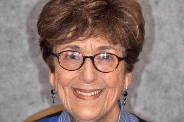Headshot photo of older woman with glasses smiling showing teeth after smile makeover
