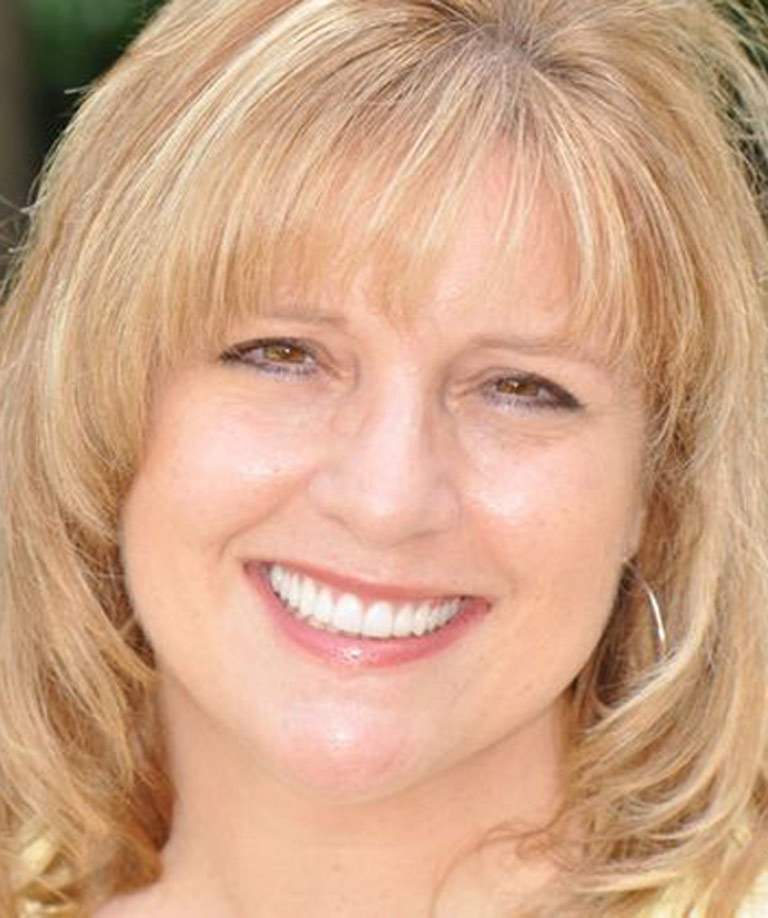 Headshot photo of middle-aged blonde woman smiling showing smile makeover results from Dr. Weiss